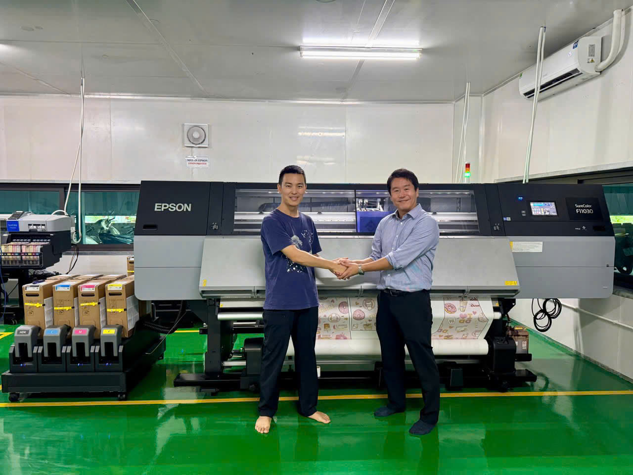 Onos Global partnership handshake beside an Epson SureColor printer